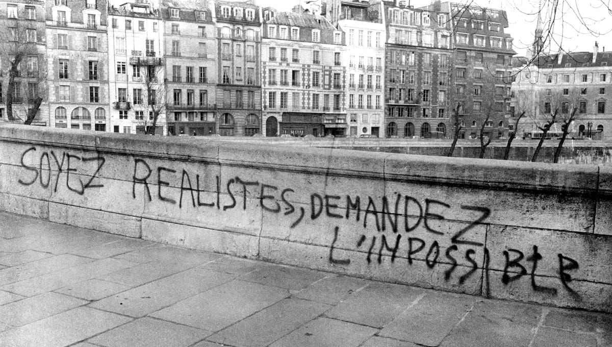 Parisian bridge graffitied with “Be reasonable, demand the impossible” in May 1968