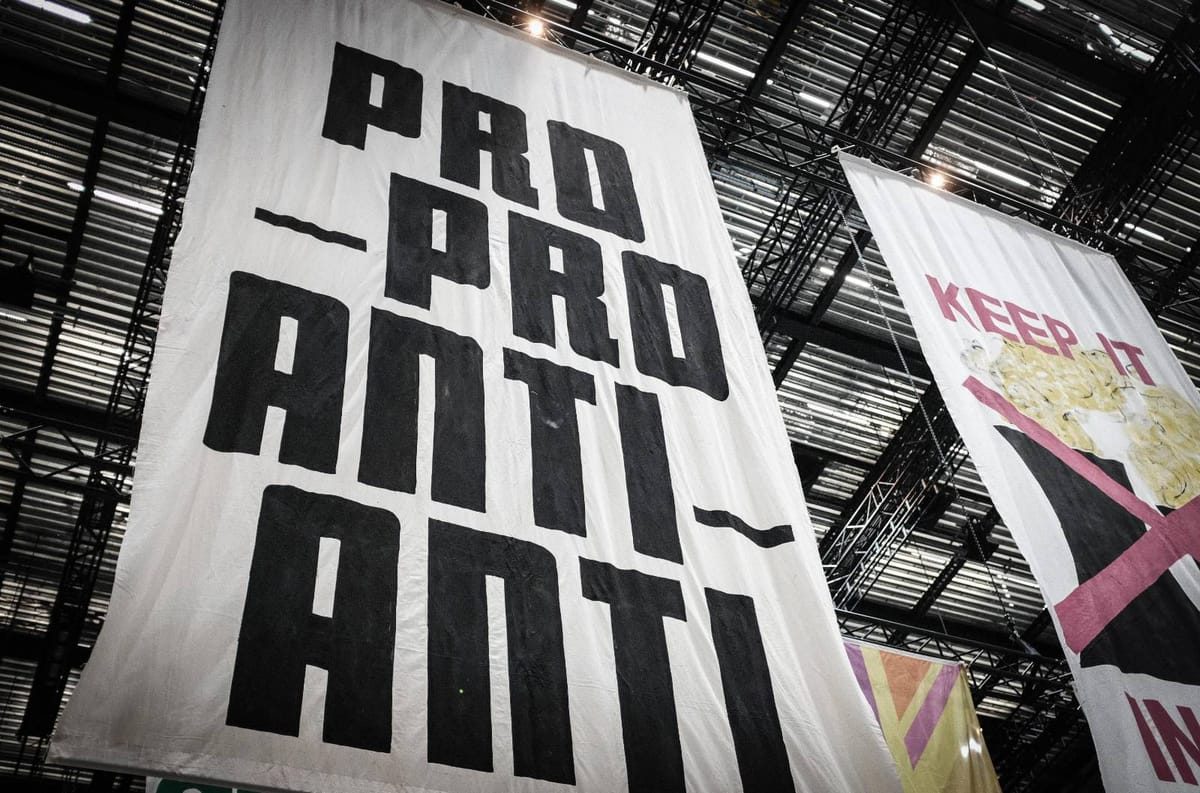 Black text of Pro-Pro Anti-Anti on a white banner hanging at Aviva Studios as part of The Fête of Britain, Feb 2024.