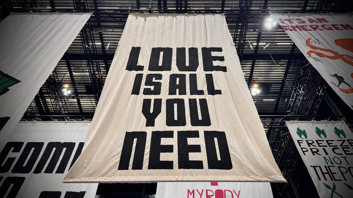 A banner reading LOVE IS ALL YOU NEED at The Fête of Britain in Manchester February 2024